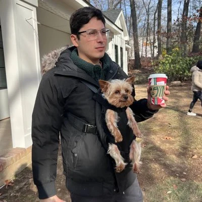 Viviano holding a Starbucks coffee with his dog in a front carrier